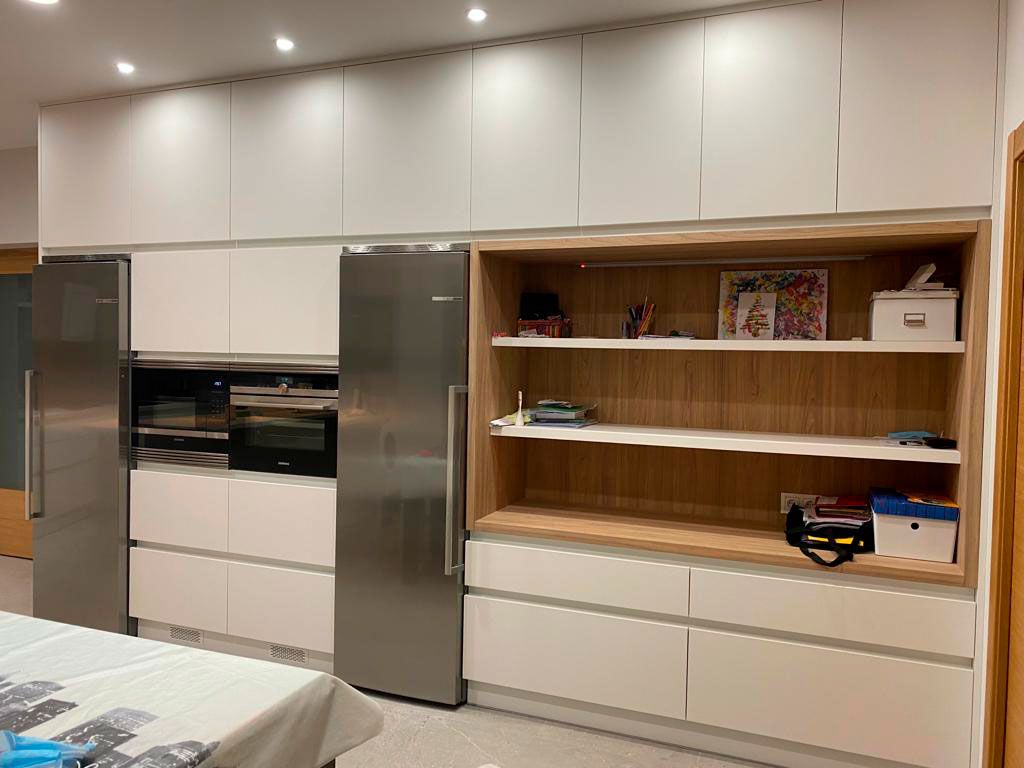 Cocina con muebles en color blanco y estantes en madera