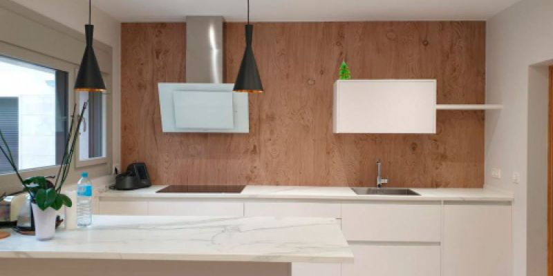 Cocina con muebles en color blanco y frontal de pared en madera