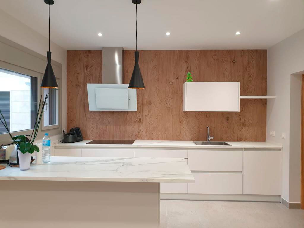 Cocina con muebles en color blanco y frontal de pared en madera