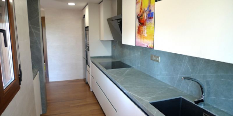 Cocina con muebles blancos y encimera en tono gris