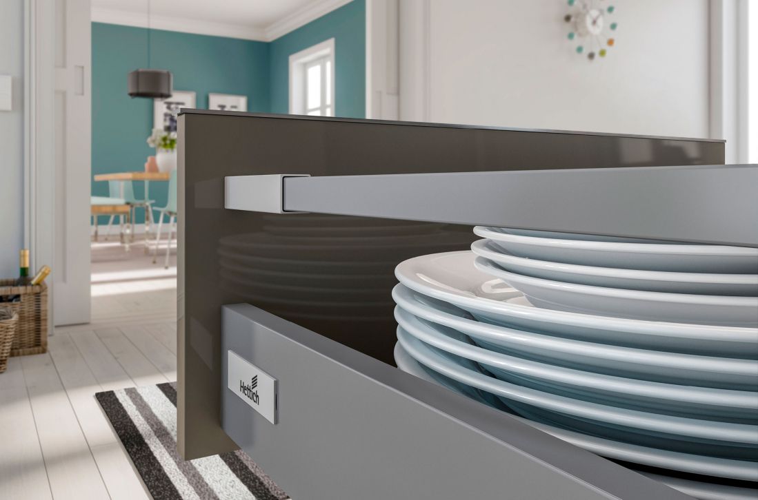 Cajonera línea de serie en color gris abierta en cocina de madera clara con platos